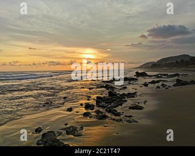 Tramonto luminoso che illumina la spiaggia con raggi dorati. Foto Stock