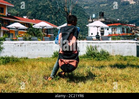 Pokhara Nepal 6 ottobre 2018 Ritratto di un giovane ragazzo nepalese che impara ad essere un pilota di parapendio nella zona di atterraggio di fronte al lago Phewa di Pokhara Foto Stock