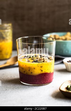 Mango, frutto della passione con Smoothie di Berries mescolato con Chia, nibs di cacao che si affettano Foto Stock