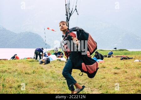 Pokhara Nepal 6 ottobre 2018 Ritratto di un giovane ragazzo nepalese che impara ad essere un pilota di parapendio nella zona di atterraggio di fronte al lago Phewa di Pokhara Foto Stock