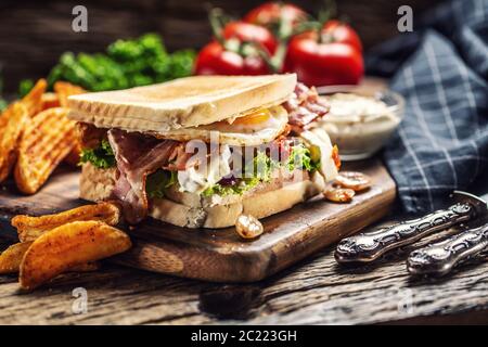 Pancetta e soleggiato lato su uovo toast alla griglia con spicchi di patate piccanti e salsa sul lato Foto Stock