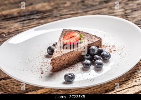 Fetta triangolare di torta di mousse al cioccolato con mirtilli e fragole Foto Stock
