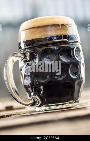 Una tazza di birra scura con schiuma Foto Stock