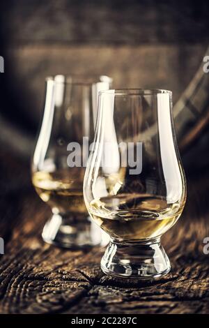 Due bicchieri da degustazione di whisky Glencairn su legno d'epoca e un barile di legno scuro sul retro Foto Stock