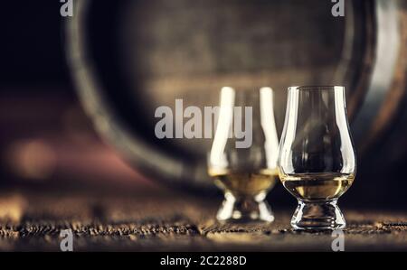 Due bicchieri da degustazione di whisky Glencairn su legno d'epoca e un barile di legno scuro sul retro Foto Stock