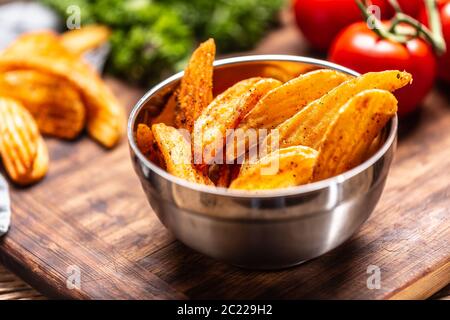 Dettaglio di spicchi di patate al forno speziati in un recipiente in metallo Foto Stock