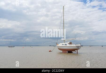 Barca in acque molto basse legate sulla spiaggia durante la bassa marea. Shoeburyness, Southend sul mare, Essex Foto Stock