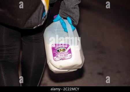 Flatbush Ave., Brooklyn il 4 giugno 2020. Una donna porta un gallone di latte in una mano guanto per aiutare con gas lacrimogeno e pepe spray infiammazione. Foto Stock