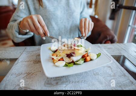 Donna di mangiare deliziosa insalata Caesar sul tavolo nel ristorante Foto Stock