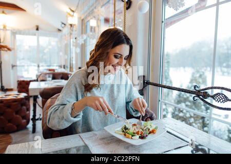 Donna sorridente mangiare insalata fresca nel ristorante Foto Stock