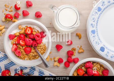 Il Granola cotta con i dadi, miscelata con fragole e yogurt, latte fresco, deliziosa di iniziare la giornata Foto Stock