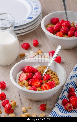 Il Granola cotta con i dadi, miscelata con fragole e yogurt, latte fresco, deliziosa di iniziare la giornata Foto Stock