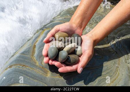 Palms tenere un mucchio di pietre in riva al mare Foto Stock