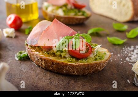 Tostare il pane toscano con pesto e prosciutto della Foresta Nera, delizioso pane fatto in casa e pesto, guarnita con parmigiano Foto Stock