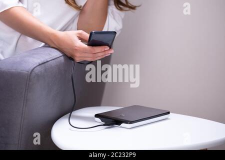 Donna in carica lo smartphone utilizzando Powerbank a casa Foto Stock