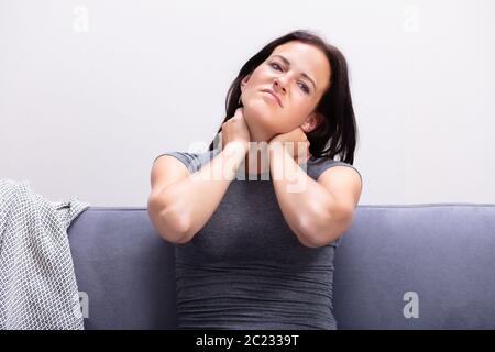Ritratto di giovane donna che soffre di dolori al collo a casa Foto Stock
