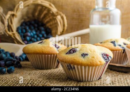 Muffin ai mirtilli latte e inceppamento in background e cesto pieno di mirtilli Foto Stock