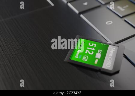 Scheda di memoria ad alta capacità su un computer portatile primo piano. SDXC 512 gb. Concetto di dispositivi di storage moderni. Vista dall'angolo superiore. Pulsanti della tastiera nel riquadro. Messa a fuoco selettiva Foto Stock