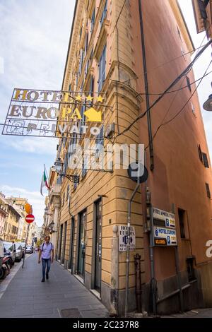 Genova - 20 agosto 2019: Un uomo cammina lungo la vecchia strada con il cartello dell'Hotel Europa a Genova, regione Liguria, Italia Foto Stock