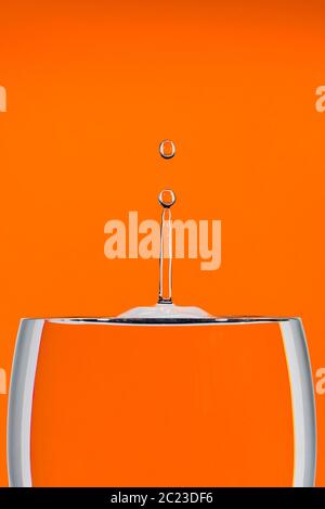 Immagine di uno studio interno di una caduta d'acqua ad alta velocità su uno sfondo arancione Foto Stock