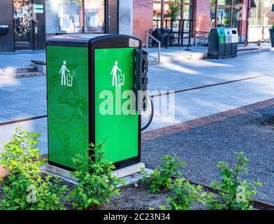 UMEA, SVEZIA - 10 GIUGNO 2020: Fresco bello verde contenitore con parte superiore nera, facile riciclaggio lattine per i turisti e locali che camminano sulla strada, estate, Foto Stock