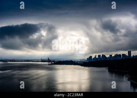 Rottura sole attraverso le nuvole scure in drammatico contrasto elevato sopra Vancouver, British Columbia, Canada. Foto Stock