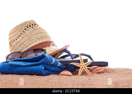 Accessori per la spiaggia: Infradito, occhiali da sole, asciugamano, cappello di paglia, giacente sulla sabbia su sfondo bianco. Concetto di vacanza e viaggio in mare. Estate backgro Foto Stock