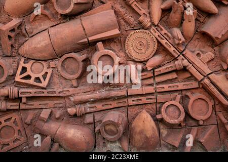 Rilievi dell'era sovietica che rappresentano armi, sul muro di terracotta, a Kutaisi, Georgia Foto Stock