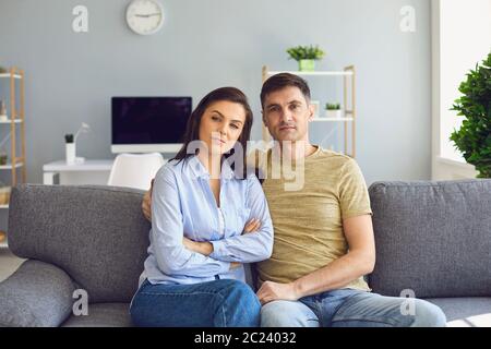 Una coppia in un umore emotivo serio con problemi guarda la macchina fotografica mentre si siede sul divano. Foto Stock