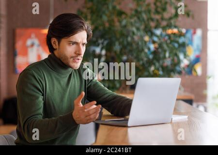 Uomo arrabbiato che guarda lo schermo del notebook, ha problemi con il lavoro Foto Stock