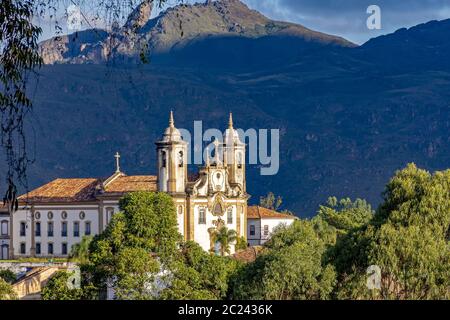 Antica chiesa cattolica storica e collina in discesa della città di Ouro Preto Foto Stock