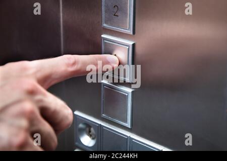 Close-up del dito umano premendo il pulsante di ascensore Foto Stock