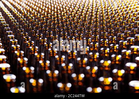 Fondo texture bottiglia di vetro. Bottiglia di vetro in fabbrica per la produzione di contenitori di vetro. Molti di vetro marrone trasparente bottiglia in fila, primo piano Foto Stock