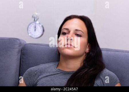 Attraente giovane donna di essere ipnotizzati con pendolo a casa Foto Stock