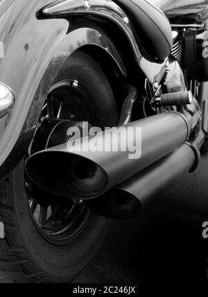 primo piano monocromatico sul retro di una moto d'epoca con parafango ruota posteriore e ampi tubi di scarico Foto Stock