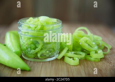 Freschi fette di banana peperoni su un tagliere con i jar pronto per il decapaggio. Foto Stock