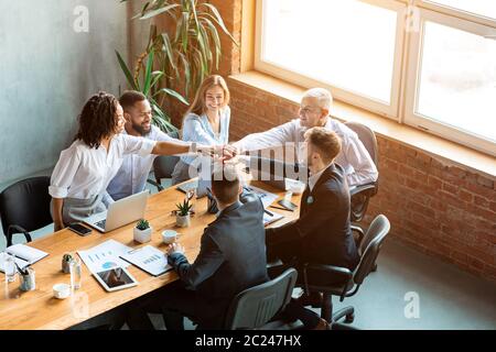 Colleghi aziendali che si occupano di tenere le mani durante la riunione di Teambuilding aziendale in ufficio Foto Stock