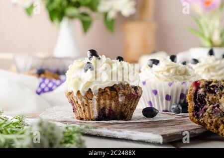 Cupcake con panna montata e bacche blu-nere da vicino. Cottura di Halloween. Ricette estive. Foto Stock