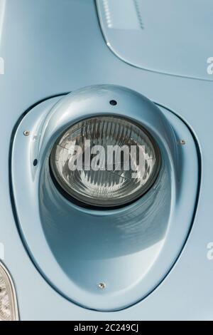 Primo piano del faro destro aperto su una vettura sportiva vintage di produzione tedesca. Foto Stock