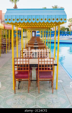 Legno per esterni terrazza ristorante con tavoli con quattro posti a sedere con un piccolo tetto contro il sole. Foto Stock