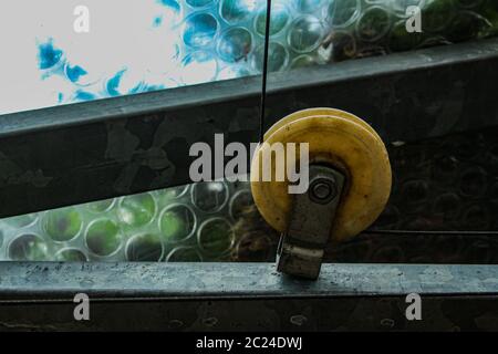 Vecchia puleggia di plastica vintage o rullo di rinvio con un cavo di acciaio intorno ad essa Foto Stock