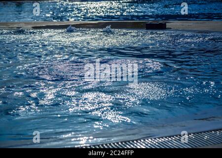 Acqua in piscina con i riflessi del sole in una calda giornata estiva Foto Stock