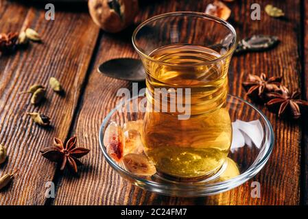 Il tè speziato con anice stellato, cardamomo e essiccato in calce armudu vetro sopra una superficie di legno Foto Stock