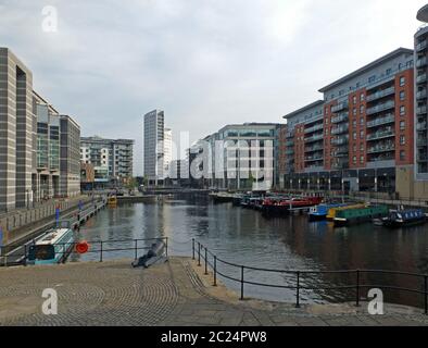 vista lungo lo sviluppo del molo clarence a leeds con edifici sul lungomare che si riflettono nelle barche d'acqua e ringhiere con serratura Foto Stock