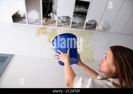 Preoccupato della donna in possesso di una benna blu al di sotto del massimale delle perdite in corridoio Foto Stock