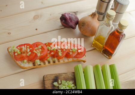 Baguette alla griglia con pomodori grigliati, olio di oliva e di sedano tagliato Foto Stock