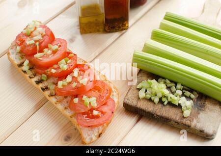 Baguette alla griglia con pomodori grigliati, olio di oliva e di sedano tagliato Foto Stock