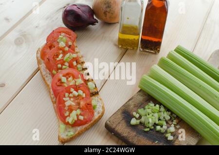 Baguette alla griglia con pomodori grigliati, olio di oliva e di sedano tagliato Foto Stock