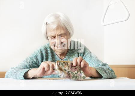 Allegro anziani 96 anni donna seduta al tavolo a casa felice con la sua pensione risparmi nel suo portafoglio dopo il pagamento di fatture. Il risparmio per il pensionamento di un Foto Stock
