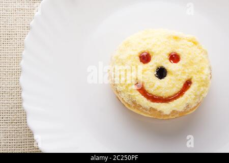 Ciambella sorridente su un piatto bianco Foto Stock